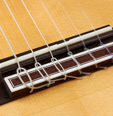 The bridge, tie-block and saddle of a 2023 Hermanos Camps "CL20-S" classical guitar made of spruce and exotic ebony