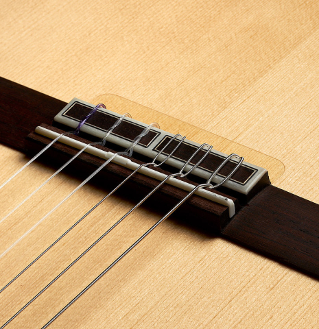 The bridge, tie-block and saddle of a 2024 Hermanos Camps "CL20-S" classical guitar made of spruce and exotic ebony