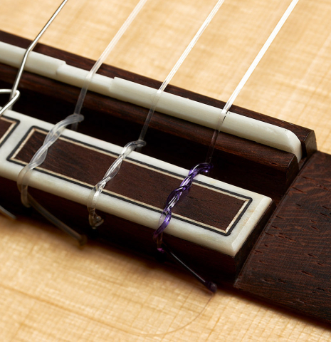 The bridge, tie-block and saddle of a 2024 Hermanos Camps "CL20-S" classical guitar made of spruce and exotic ebony