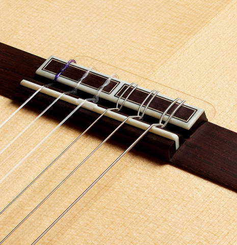 The bridge, tie-block and saddle of a 2024 Hermanos Camps "CL20-S" classical guitar made of spruce and exotic ebony