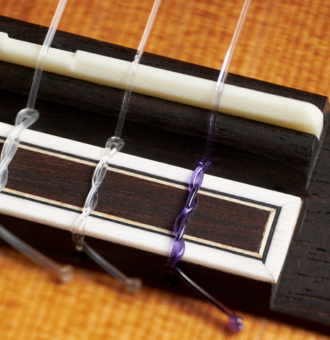 The bridge, tie-block and saddle of a 2023 Hermanos Camps "CL20-C" classical guitar made of cedar and exotic ebony