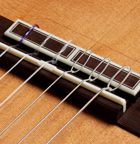 The bridge, tie-block and saddle of a 2024 Hermanos Camps "CL20-C" classical guitar made of cedar and exotic ebony