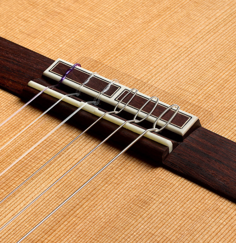 The bridge, tie-block and saddle of a 2025 Hermanos Camps "CL20-C" classical guitar made of cedar and exotic ebony