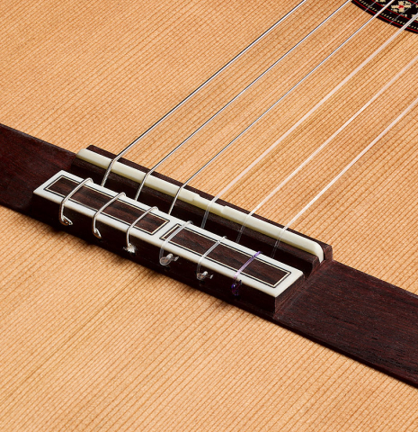 The bridge, tie-block and saddle of a 2026 Hermanos Camps "CL20-C" classical guitar made of cedar and exotic ebony