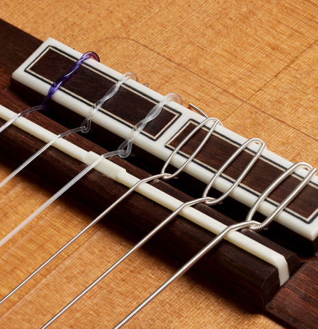 The bridge, tie-block and saddle of a 2024 Hermanos Camps "CL20-C" classical guitar made of cedar and Malaysian blackwood