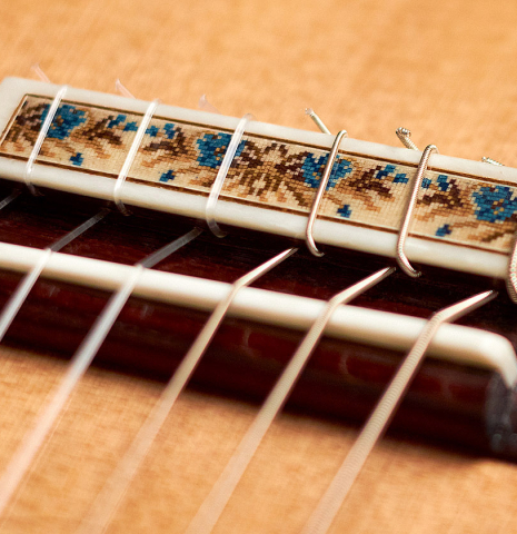 The bridge and saddle of a 2021 Vicente Carrillo "Maestro Double Top" classical guitar made with cedar soundboard and African rosewood back and sides