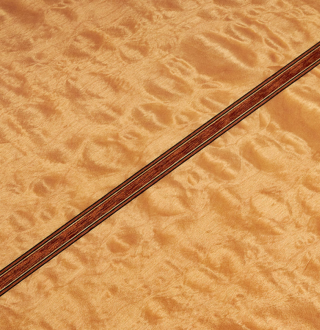 The close-up of the maple back of a 2022 Vicente Carrillo &quot;Maestro Double Top&quot; classical guitar made with spruce top