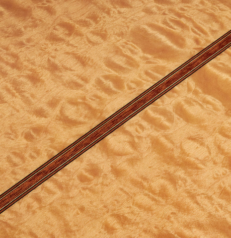 The close-up of the maple back of a 2022 Vicente Carrillo "Maestro Double Top" classical guitar made with spruce top
