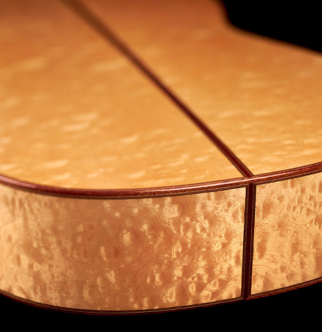 The maple back and sides of a 2022 Vicente Carrillo "Maestro Double Top" classical guitar made with spruce top