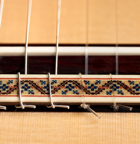 The bridge and saddle of a 2022 Vicente Carrillo "Maestro Double Top" classical guitar made with spruce top