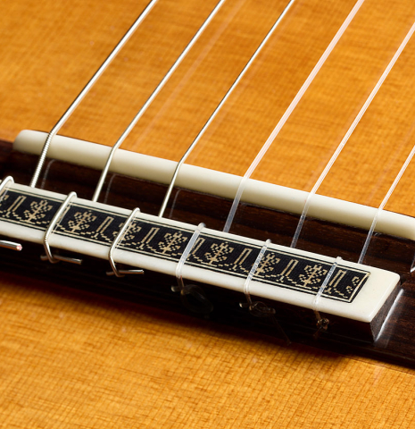 The bridge, tie-block and saddle of a 2024 Vicente Carrillo "Herencia" classical guitar made of cedar and Indian rosewood