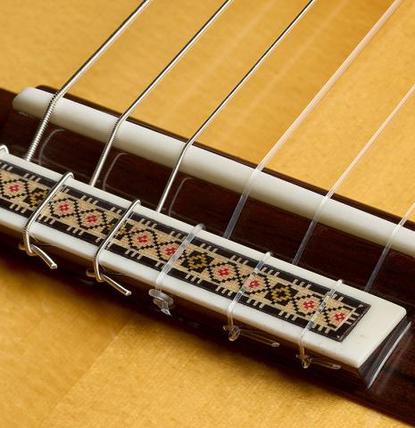 The bridge, tie-block and saddle of a 2025 Vicente Carrillo "Primera Especial" classical guitar made of spruce and Malaysian blackwood