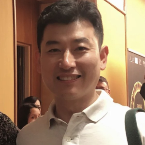 Portrait of Korean guitar maker Moonseok Choi smiling at the Rome Guitar Expo in 2022