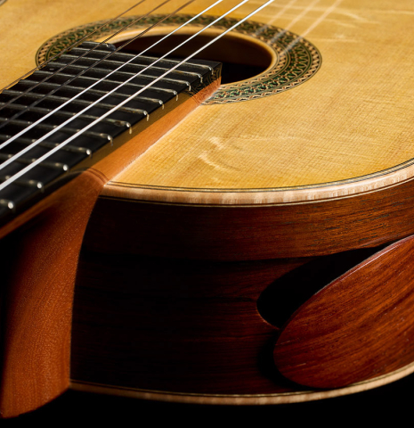 The elevated fingerboard of a 2017 Stephan Connor "640" classical guitar made of spruce and African rosewood