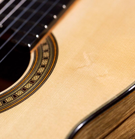 The soundboard and rosette of a 2020 Luis Fernandez de Cordoba classical guitar made of spruce and black limba wood.