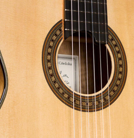 The soundboard and rosette of a 2020 Luis Fernandez de Cordoba classical guitar made of spruce and black limba wood.