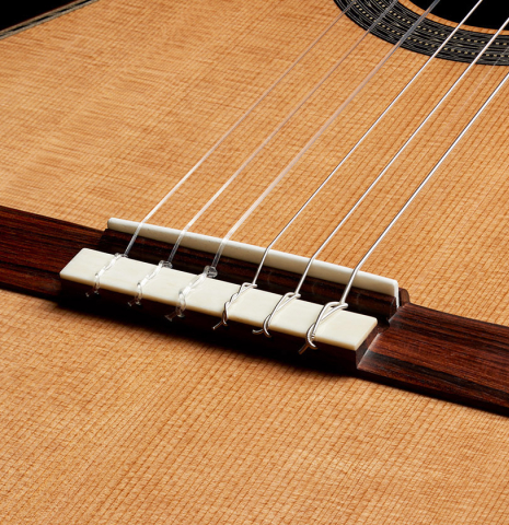 The bridge, tie-block and saddle of a Cordoba Guitars Master Series "Torres Lefty" classical guitar made of cedar and Indian rosewood