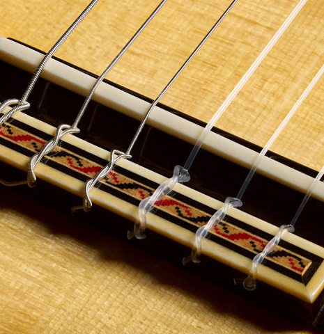 The bridge, tie-block and saddle of a 2026 Andy Culpepper "Santos" classical guitar made of spruce and maple