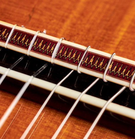The ornamented bridge of a 1990 Matthias Dammann classical guitar (ex Pepe Romero) made of cedar and CSA rosewood