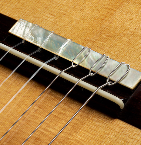 The bridge, tie-block and saddle of a 2025 Francesco De Gregorio "Torres, SE 111" classical guitar made of spruce and maple
