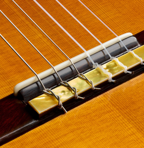 The bridge, tie-block and saddle of a 2025 Francesco De Gregorio "Torres, SE 111" classical guitar made of spruce and maple