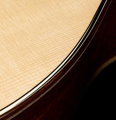 The top binding and purfling of a 2023 Marc Dickinson "Cosmic" classical guitar made of spruce and Indian rosewood