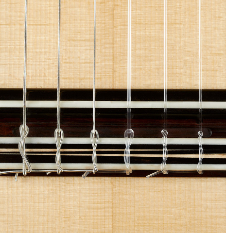 The bridge, tie-block and saddle of a 2023 Marc Dickinson "Cosmic" classical guitar made of spruce and Indian rosewood