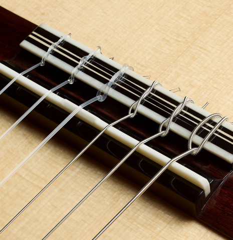 The bridge, tie-block and saddle of a 2025 Marc Dickinson "Cosmic" classical guitar made of spruce and Indian rosewood