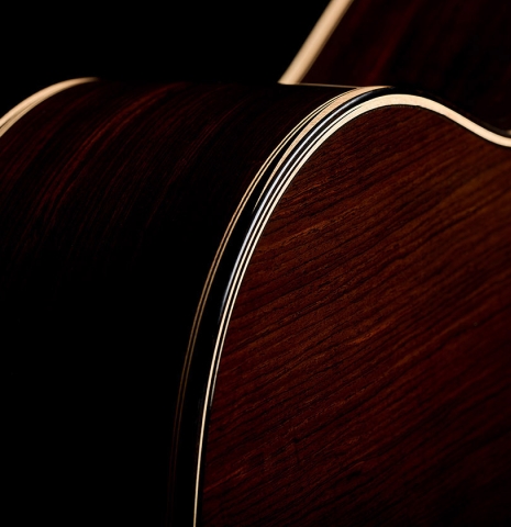The bindings and purflings on the back and sides of a 2026 Marc Dickinson "Cosmic" classical guitar made of spruce and African blackwood