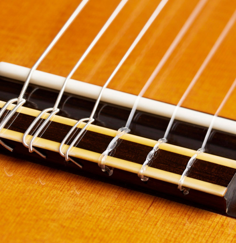 The bridge, tie-block and saddle of a 2024 Vladimir Druzhinin classical guitar made with cedar and African rosewood.
