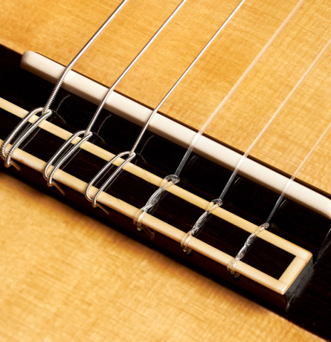 The bridge of a 2023 Vladimir Druzhinin classical guitar made with spruce and African rosewood.