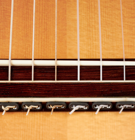 The bridge and tie block of a 1994 Jeffrey Elliott classical guitar made with spruce and Indian rosewood.