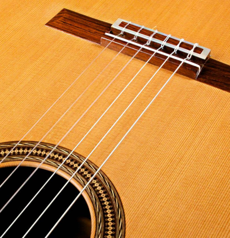 The bridge and nylon strings of a 2007 Antonio Raya Ferrer classical guitar made of cedar and Indian rosewood