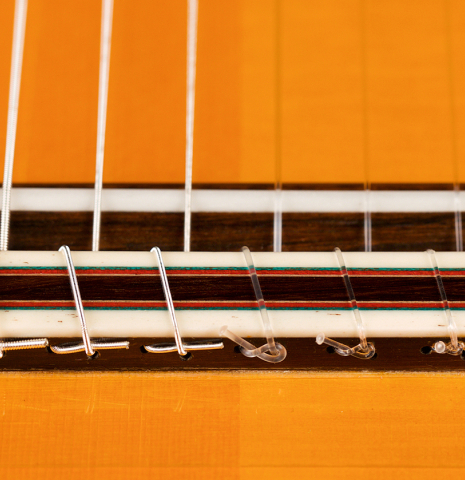 The bridge, saddle and tie-block of a 2021 Gerundino Fernandez Hijo &quot;Negra&quot; flamenco guitar made with spruce and pau ferro