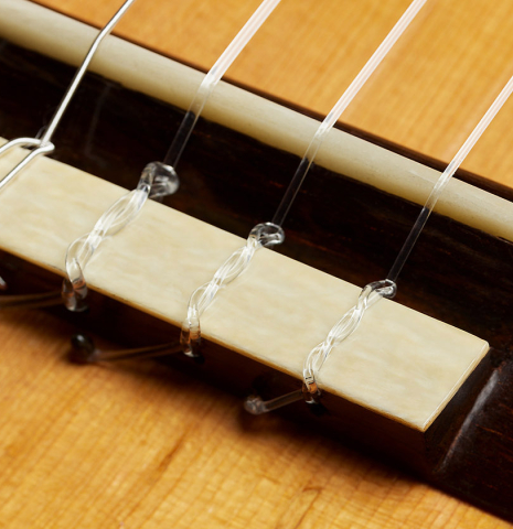 The bridge, tie-block and saddle of a 1992 Dominique Field classical guitar made of spruce and Indian rosewood