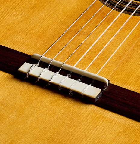 The bridge, tie-block and saddle of a 2026 Liuteria Frignani "1910 Manuel Ramirez" classical guitar made of spruce and Indian rosewood