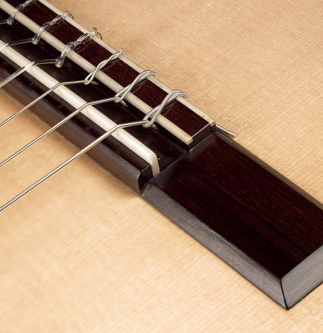Detail of the bridge, tie-block and saddle of a 2023 Hironori Fukuda classical guitar made with spruce and CSA rosewood