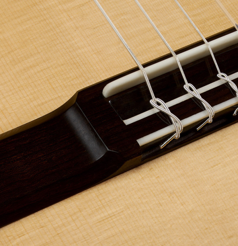 The bridge, tie-block and saddle of a 2026 Hironori Fukuda classical guitar made of spruce and maple