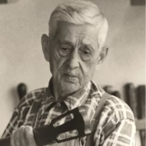 Black-and-white photo of an elderly Pietro Gallinotti holding a guitar by its headstock