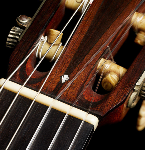 The nut and head veneer with inlay of a 1918 Enrique Garcia classical guitar made of spruce and CSA rosewood