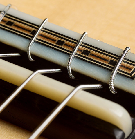 The bridge, tie-block and saddle of a 2023 Francisco Navarro Garcia classical guitar made of spruce and Indian rosewood