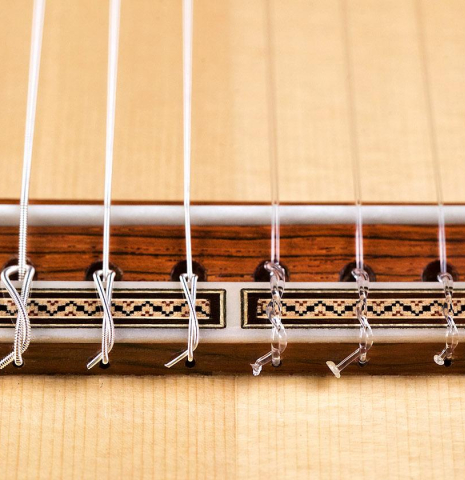 The bridge and saddle of a 2017 Ennio Giovanetti classical guitar made with spruce top and CSA rosewood back and sides