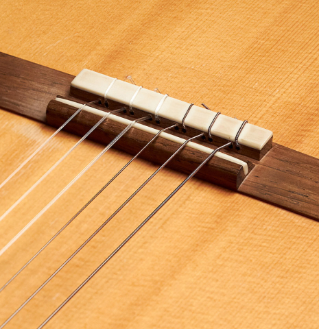 The bridge and tie block of a 1991 Gioachino Giussani classical guitar made of spruce and maple.