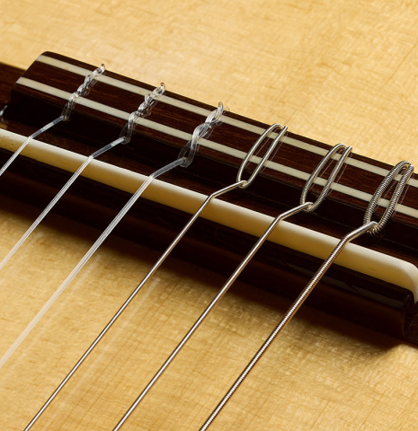 The bridge, tie-block and saddle of a 2025 Mario Grimaldi "1920 Santos" classical guitar made of spruce and African rosewood