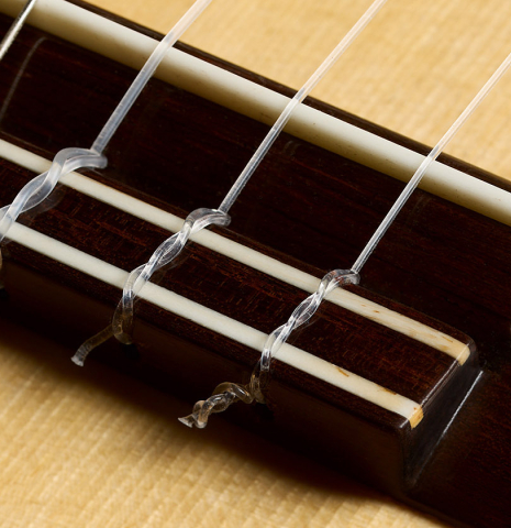 The bridge, tie-block and saddle of a 2026 Mario Grimaldi "1920 Santos" classical guitar made of spruce and African rosewood