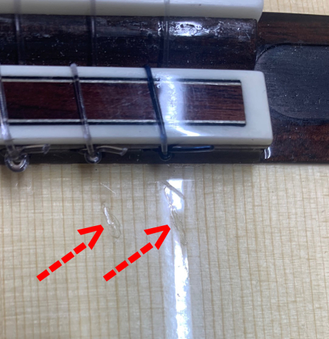 Two dings behind the bridge of a 2021 Yulong Guo "Chamber Concert" classical guitar made with spruce top and Indian rosewood back and sides.