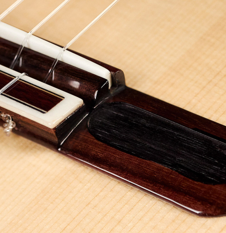 The bridge of a 2021 Yulong Guo &quot;Chamber Concert&quot; classical guitar made with spruce top and Indian rosewood back and sides.
