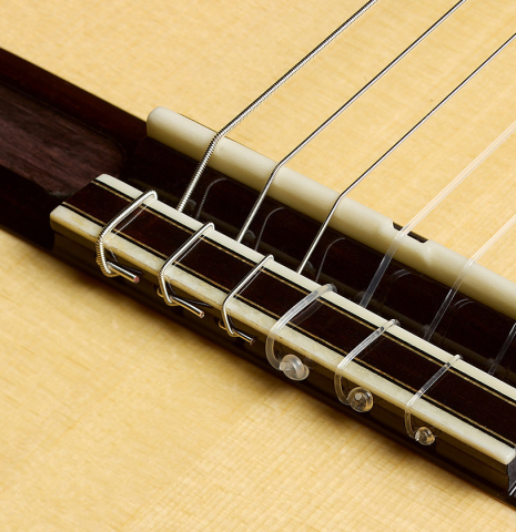 The bridge, tie-block and saddle of a 2018 Yulong Guo "Chamber Concert" classical guitar made of spruce and Indian rosewood