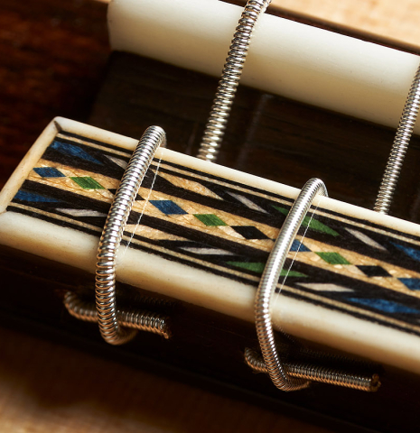 The bridge, tie-block and saddle of a 2023 Miguel Angel Gutierrez classical guitar made of spruce and Indian rosewood.