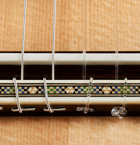 The bridge, tie-block and saddle of a 2024 Miguel Angel Gutierrez classical guitar made of spruce and Indian rosewood.